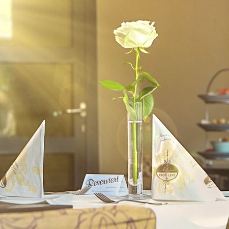 Elegant gedeckter Tisch mit einer weißen Rose in einer Vase