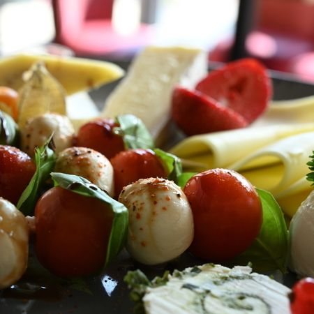 Eine Käseplatte mit Mozzarellakugeln, Tomaten, Basilikum und verschiedenen Käsescheiben