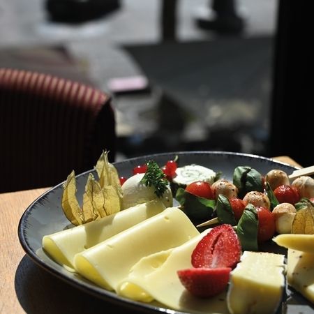 Käseplatte mit Früchten und aufgespießten Tomaten und Mozzarella