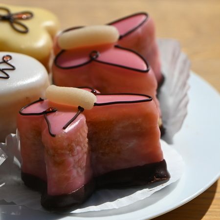 Verschiedene Petit Fours mit dekorativer Glasur auf einem weißen Teller.